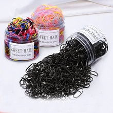 Close-up of colorful elastic hair bands in transparent jars on white silk background