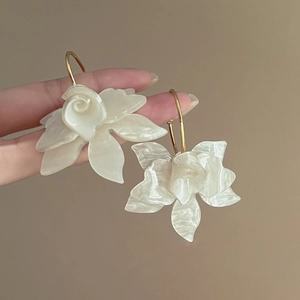 Détail de boucles d'oreilles camélia blanc crème montrant la texture et la taille