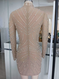 Détail d'une robe moulante nude ornée de perles blanches et de franges de strass étincelants