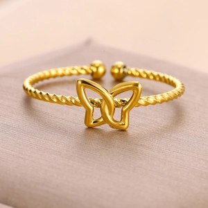 Detailed close-up of a golden open bangle with twisted wire design and butterfly center