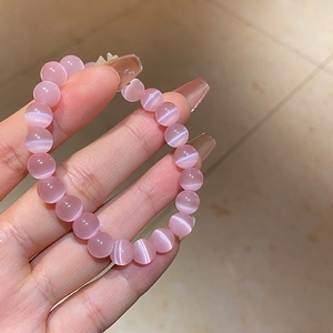 Detailed macro view of pink cat eye stone beads on an elastic bracelet worn on wrist