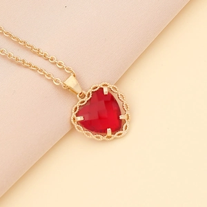 Elegant gold necklace with a vibrant red heart-shaped zircon pendant on soft fabric
