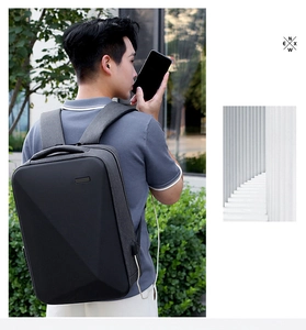 Macro detail of black hardshell backpack with geometric texture and integrated USB port
