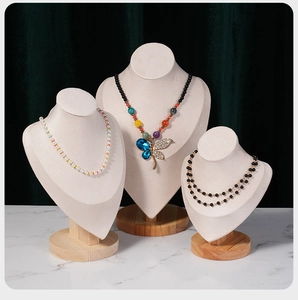 Detailed view of necklace busts with velvet texture on a natural beech wood base