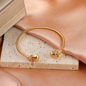 Bracelet gothique tête de mort doré sur travertin beige avec fond en satin champagne
