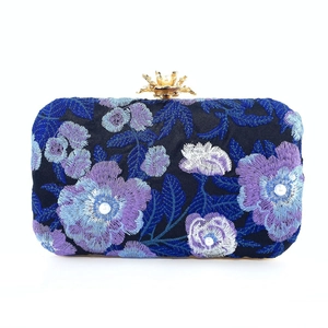 Detailed embroidery on a navy evening clutch bag with blue flowers and pearl clasp