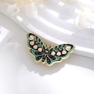 Detailed macro of enamel butterfly brooch with pink lily and golden celestial patterns