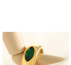 Détail d'une bague large dorée avec émeraude verte de taille marquise sur une main en bois
