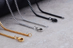 Dettaglio macro di catene box in acciaio inossidabile oro, argento e nero con moschettoni