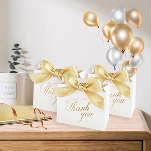 Trois sacs cadeaux en papier blanc avec texte Thank You doré et nœuds en ruban rose