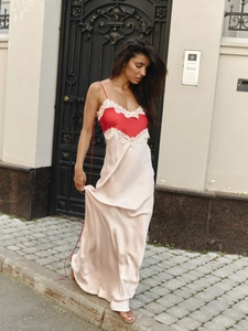 Satin champagne slip dress with red lace trim standing in front of a vintage door
