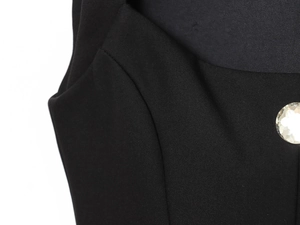 Close-up of black woven fabric with a sparkling faceted rhinestone decorative button