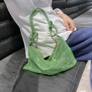 Detail view of vibrant green rhinestone hobo bag with knotted handle being carried