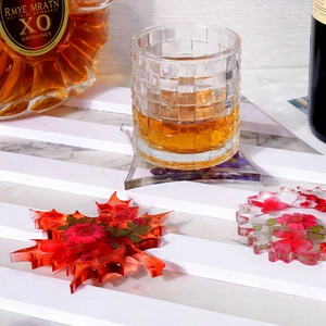 Detail of leaf-shaped resin coaster with embedded real dried flowers on a wooden stand