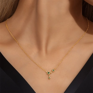 Close-up of a gold necklace with a green gemstone star pendant on a female model