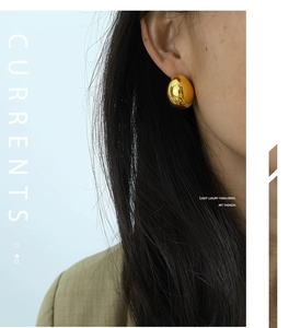 Close-up of a polished gold teardrop earring with a high-shine liquid metal finish