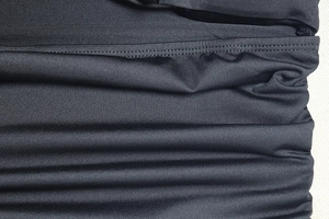Vue macro des coutures du tissu noir extensible et de la texture plissée sur la robe