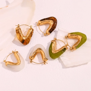 Detailed shot of V-shaped gold earrings with amber, white and green resin inlays