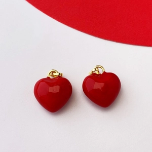 Close-up of red enamel heart pendants with gold hanging loops on a white background