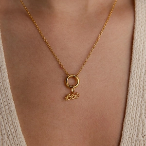 Detailansicht der goldenen Sternzeichen-Halskette mit Kristallen an einem Model in Strick