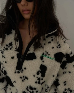 Detail eines Plüsch-Sweatshirts mit Kuhmuster, Viertel-Reißverschluss und Stickerei