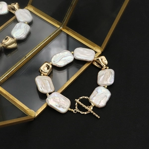 Detailed macro view of baroque pearl bracelet with gold geometric beads and OT toggle clasp