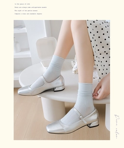 Hellblaue gerippte Baumwollsocken kombiniert mit silbernen Mary Janes und gepunktetem Rock
