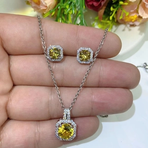 Macro detail of silver necklace and earring set with yellow square zircon stones