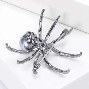 Detailed close-up of a spider brooch featuring grey pearls and intricate metal leg textures