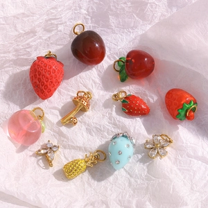 Vue détaillée des breloques fraises et papillons dorés 18K pour la création de bijoux