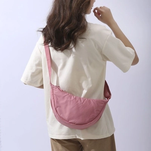 Pink nylon half-moon crossbody dumpling bag shown on model with minimalist design