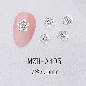 Macro detail of 7mm silver alloy flower nail charms with central crystal on pink manicure