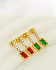 Detail view of gold earrings with rectangular red/green crystals and white pearls