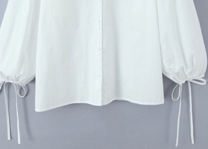 Detail of white long sleeve shirt showing the drawstring cuff and pearl buttons
