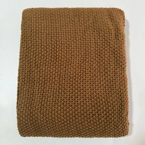 Detailed view of brown waffle knit blanket with thick texture and tassel fringe edges