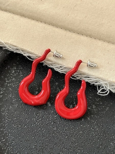 Close-up of red hollow line earrings with glossy finish and silver needle design