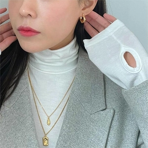 Close-up of geometric gold-plated earrings and double-layered necklace on a model
