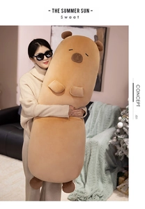 Close-up of extra large long capybara plush pillow held by a girl in a cozy room