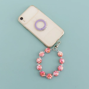 Close-up of pink cat paw beaded phone strap attached to a clear case on blue background