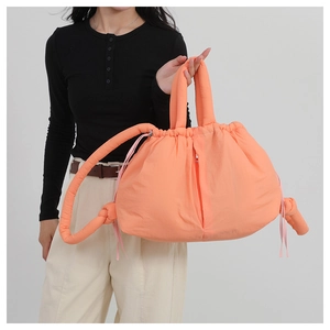 Detail of a bright orange puffy nylon tote bag with drawstring and quilted bubble texture