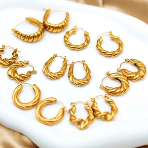 Detail of assorted gold plated twisted rope hoop earrings on a white display tray