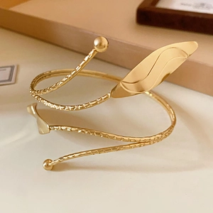 Detailed view of golden leaf spiral upper arm cuff with embossed textures and round beads