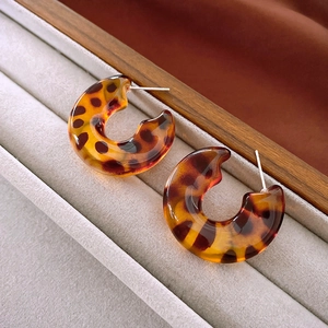 Macro detail of leopard print C-shape resin hoop earrings with silver needle posts