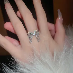 Elegant silver tassel zircon ring with bow design and shimmering stones on a finger