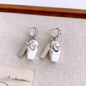 Macro shot of silver teddy bear earrings with heart-shaped gemstones on linen