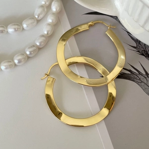 Minimalist large golden hoop earrings in flat circular design with polished finish