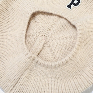 Detailed close-up of cream knit beret showing the soft texture and letter P patch