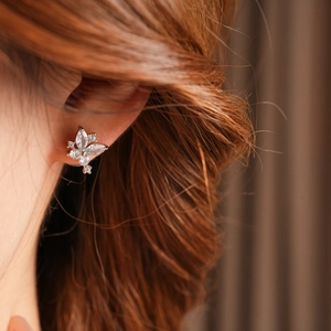 Gros plan d'une boucle d'oreille papillon en zircone portée par un mannequin en finition or