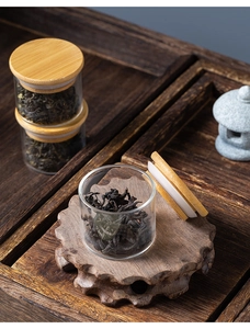 Mini glass tea jars with bamboo lids displayed on a wooden tray for travel storage