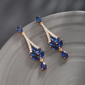 Detailed view of luxury gold-plated drop earrings with blue cubic zirconia stones